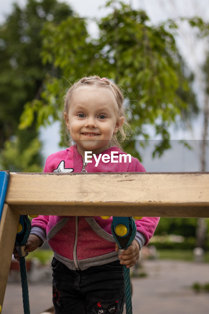 PORTRAIT OF CUTE GIRL HOLDING WOOD