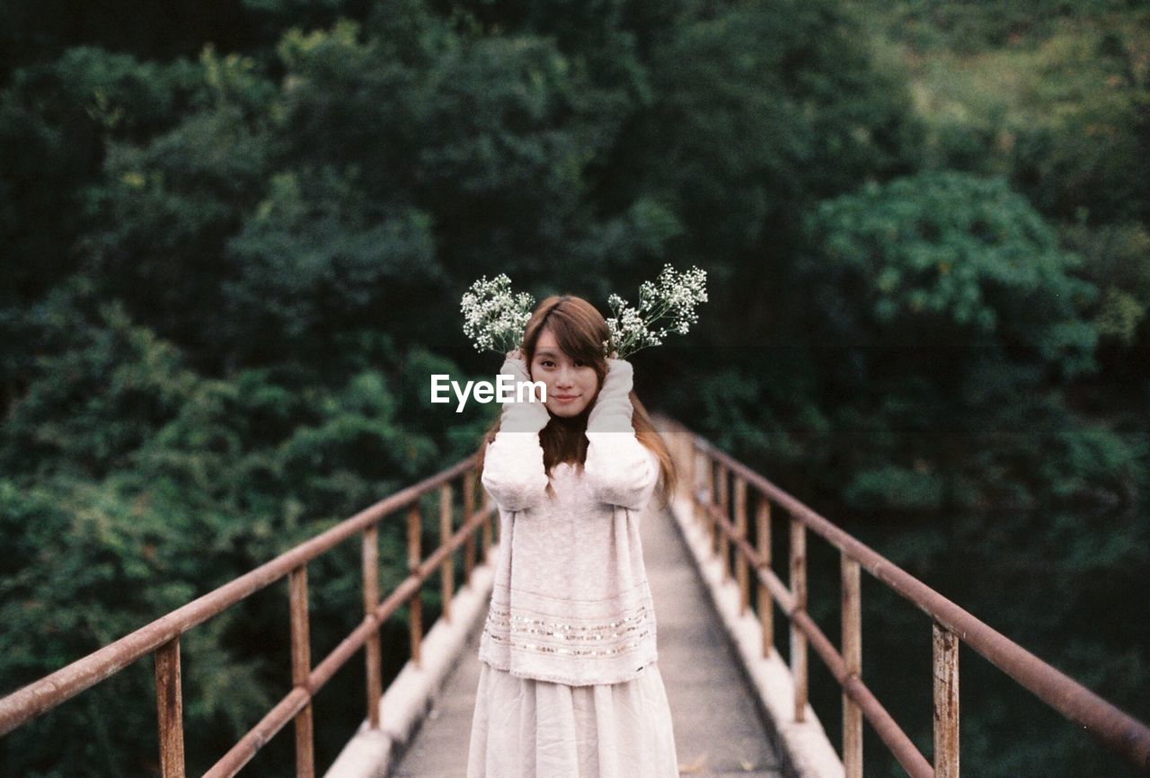 Portrait of a young woman standing on footbridge