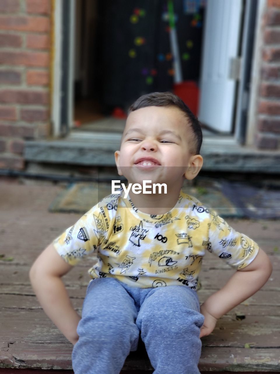 Cheerful cute boy sitting in porch