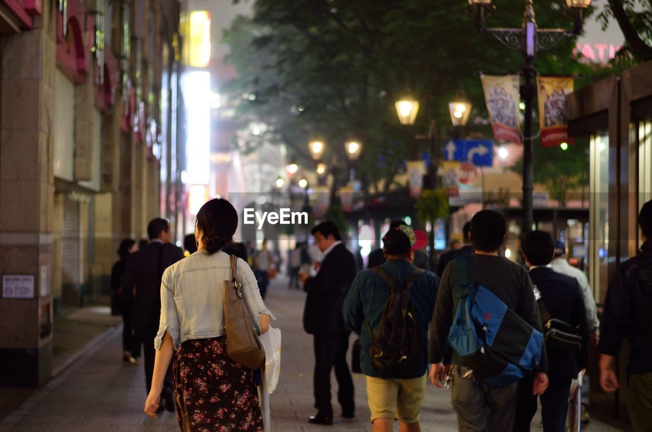 Women with purse walking on busy street 