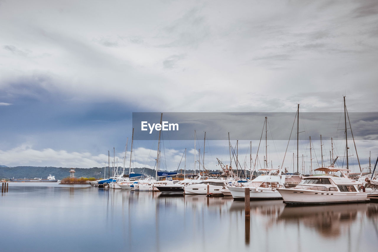 Boats moored at harbor against sky