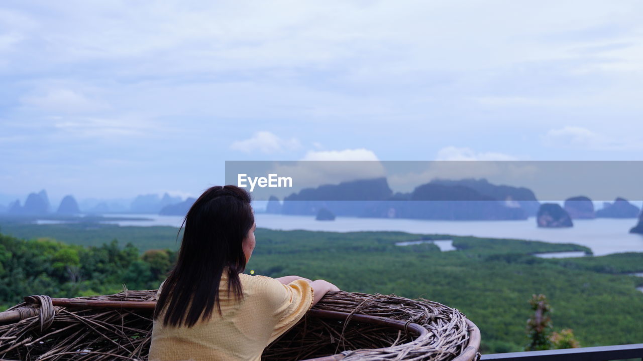 Rear view of woman looking at mountain against sky