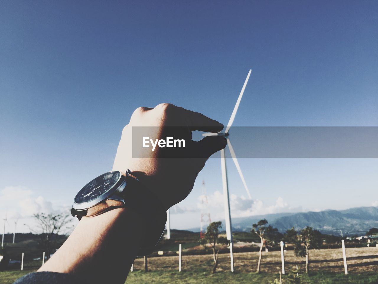 Optical illusion of man holding wind turbine