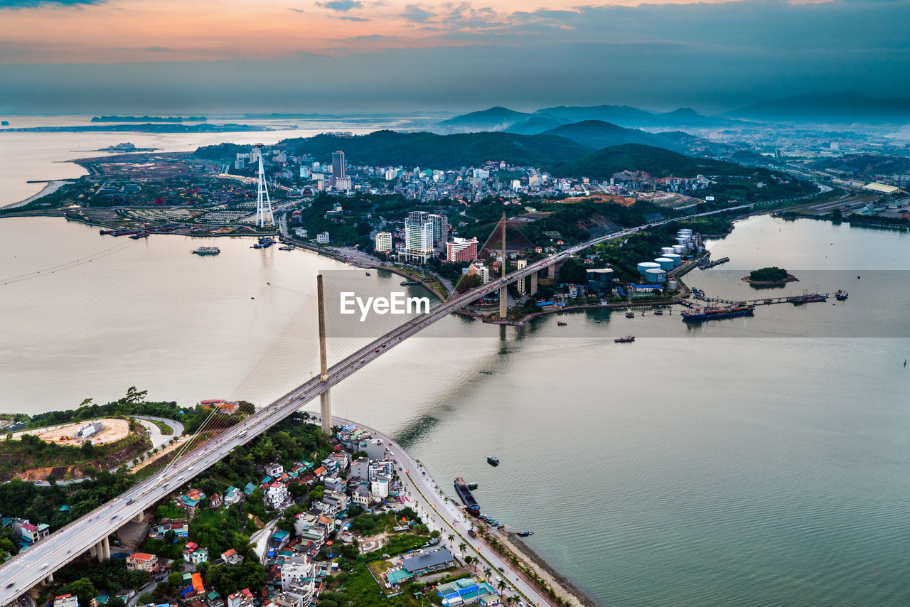 Aerial view of bridge over bay in city during sunset