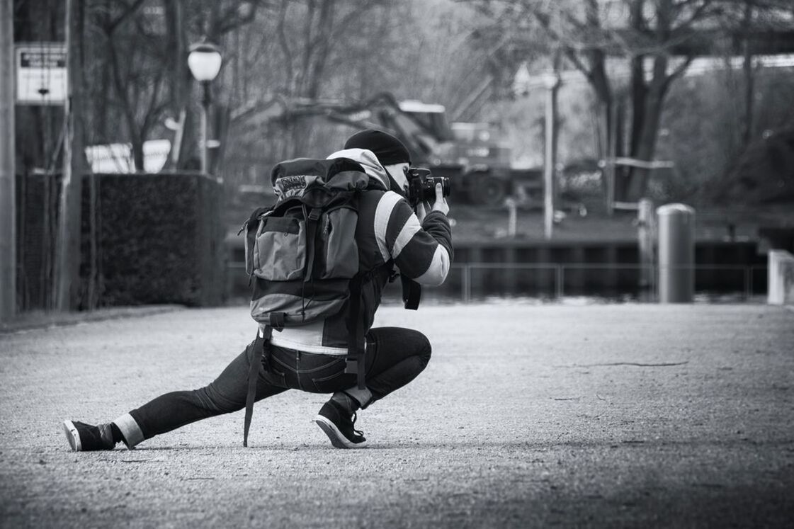 Full length of photographer photographing while crouching on street