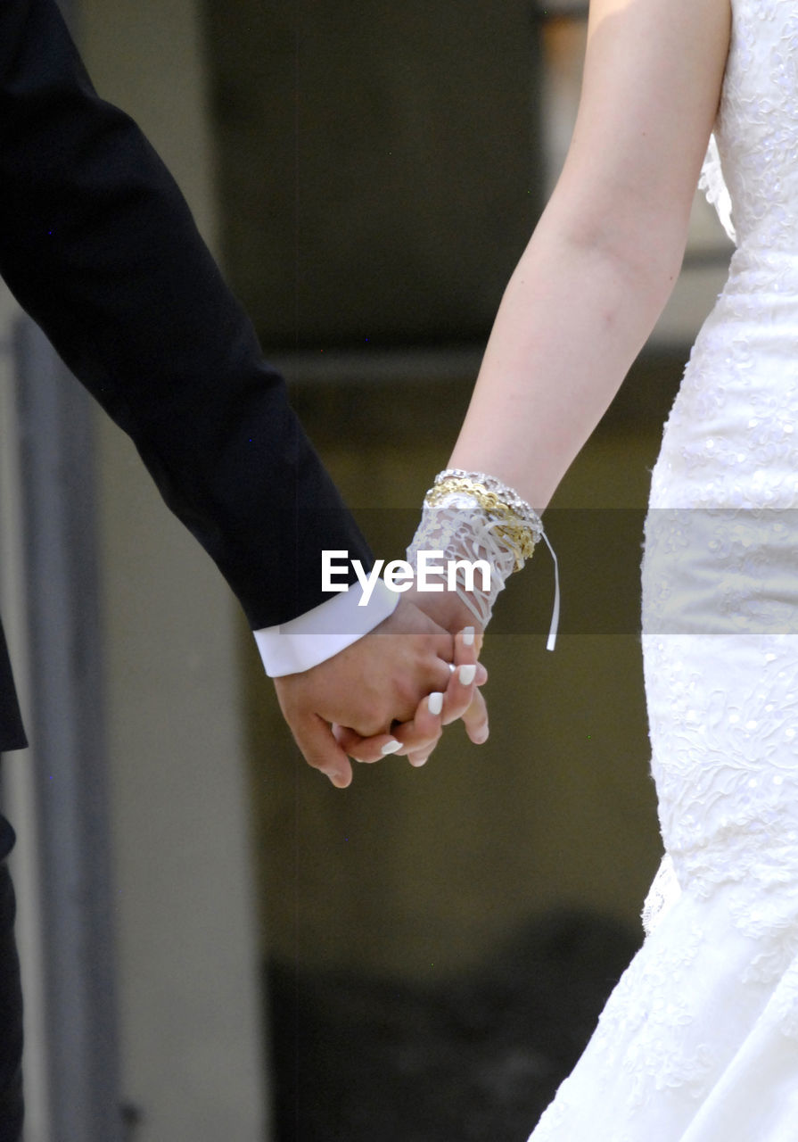 Midsection of couple holding hands during wedding ceremony