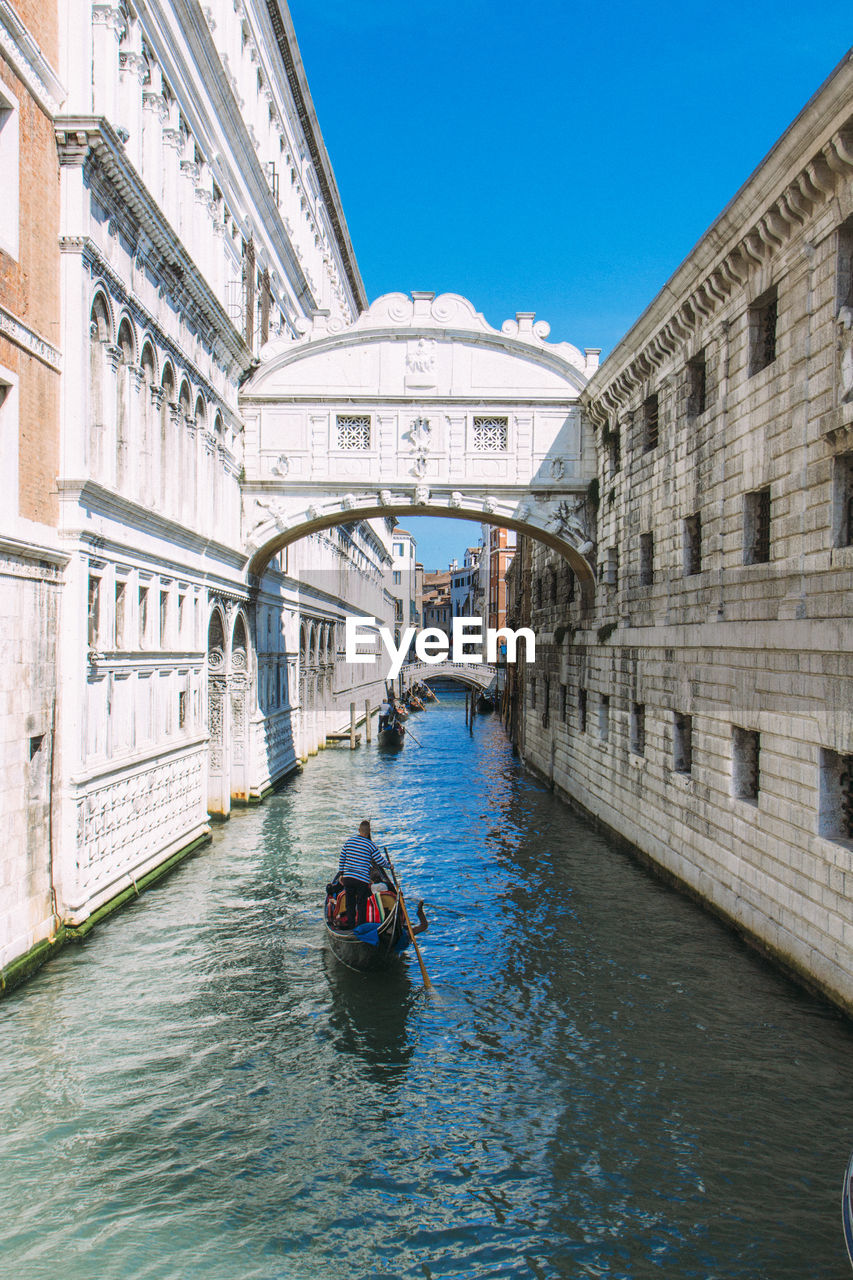 Man in gondola on grand canal against bridge of sighs