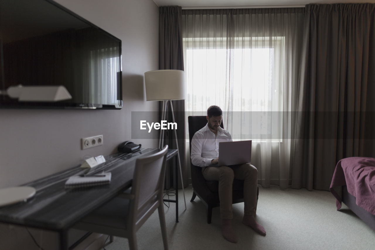 Man using laptop in bedroom