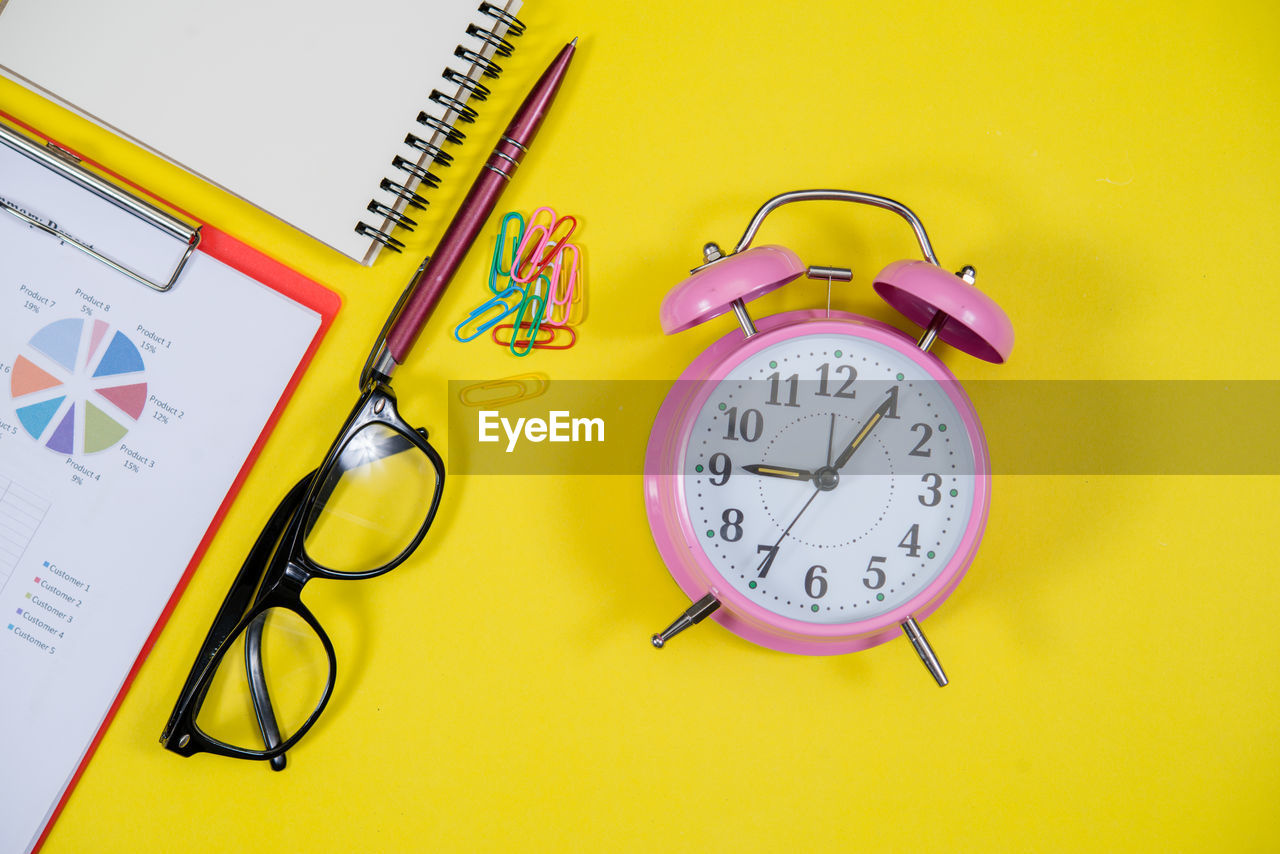 HIGH ANGLE VIEW OF CLOCK ON YELLOW TABLE