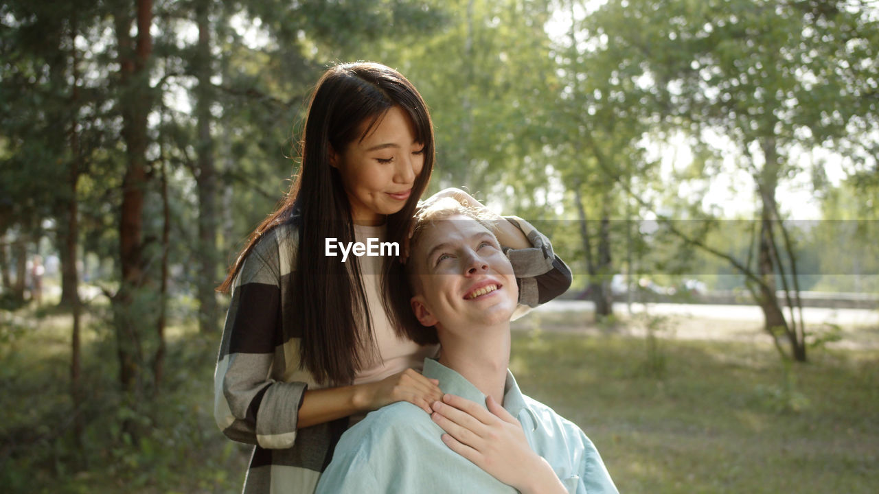 Smiling girlfriend embracing handicapped boyfriend at park