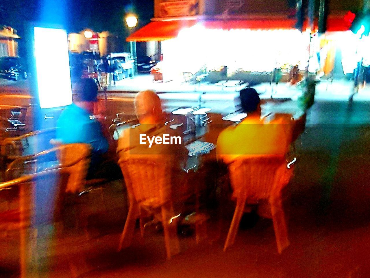 REAR VIEW OF MAN STANDING ON CITY STREET AT NIGHT