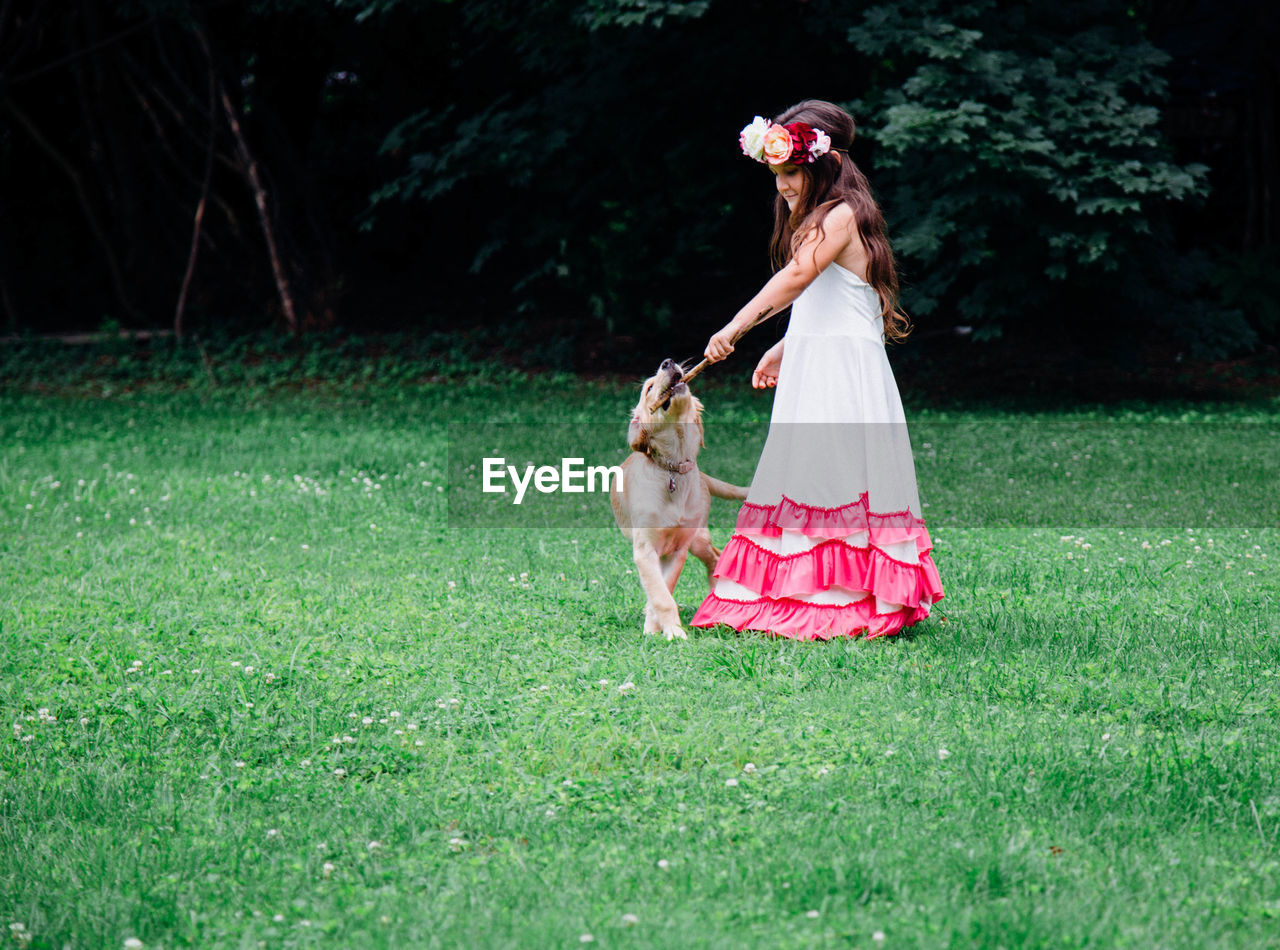 Side view of girl playing with dog on grassy field