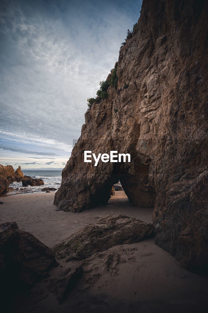 Rock formation on beach against sky