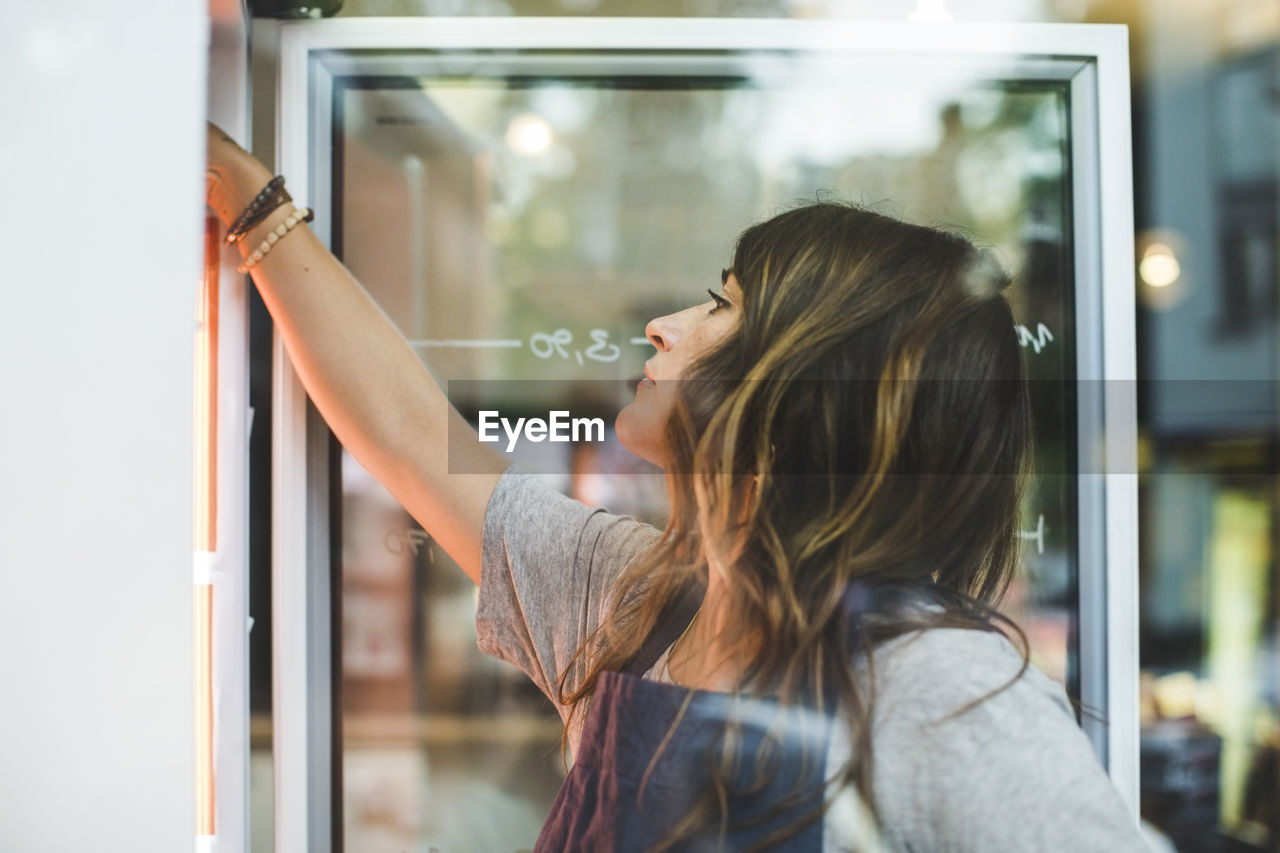 Female employee searching in refrigerator at deli