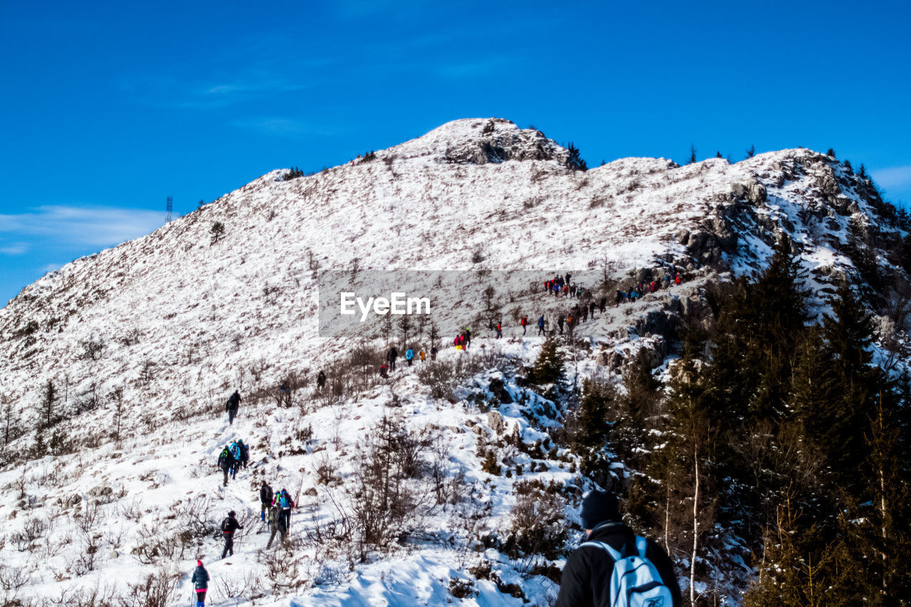 LOW ANGLE VIEW OF PEOPLE ON SNOWCAPPED MOUNTAIN