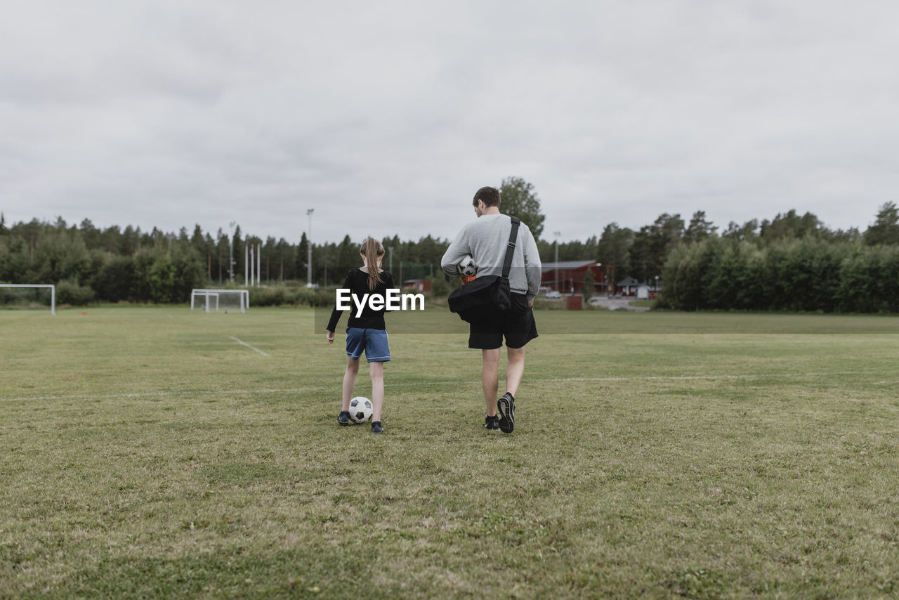 Father and daughter on football pitch