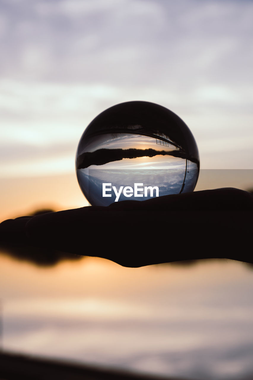 CLOSE-UP OF SILHOUETTE CRYSTAL BALL AGAINST SKY AT SUNSET