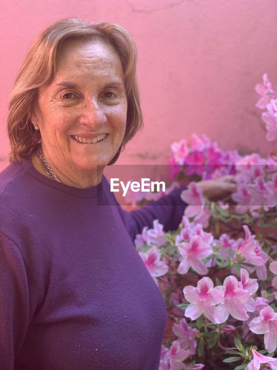 PORTRAIT OF A SMILING WOMAN WITH PINK FLOWER