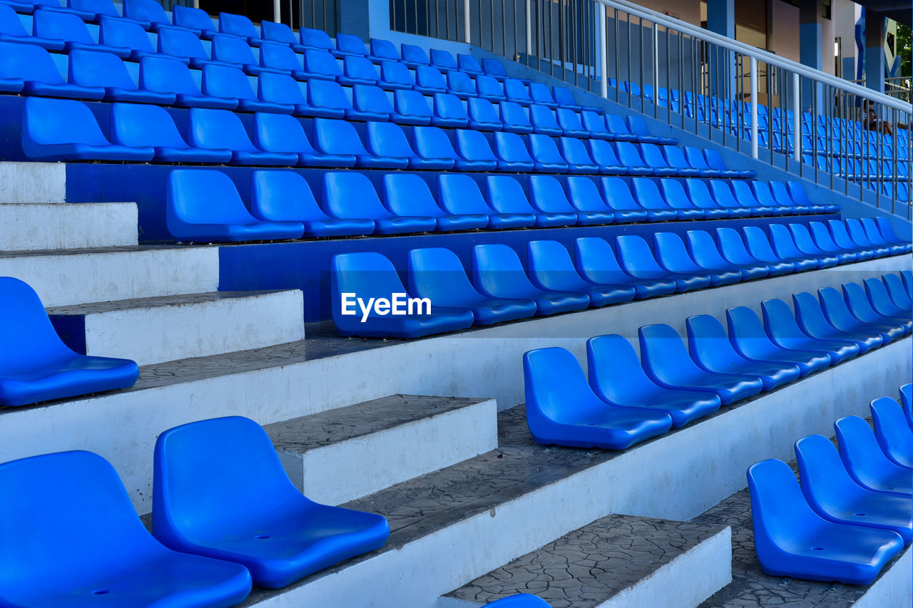 EMPTY CHAIRS AGAINST BLUE SKY IN ROW