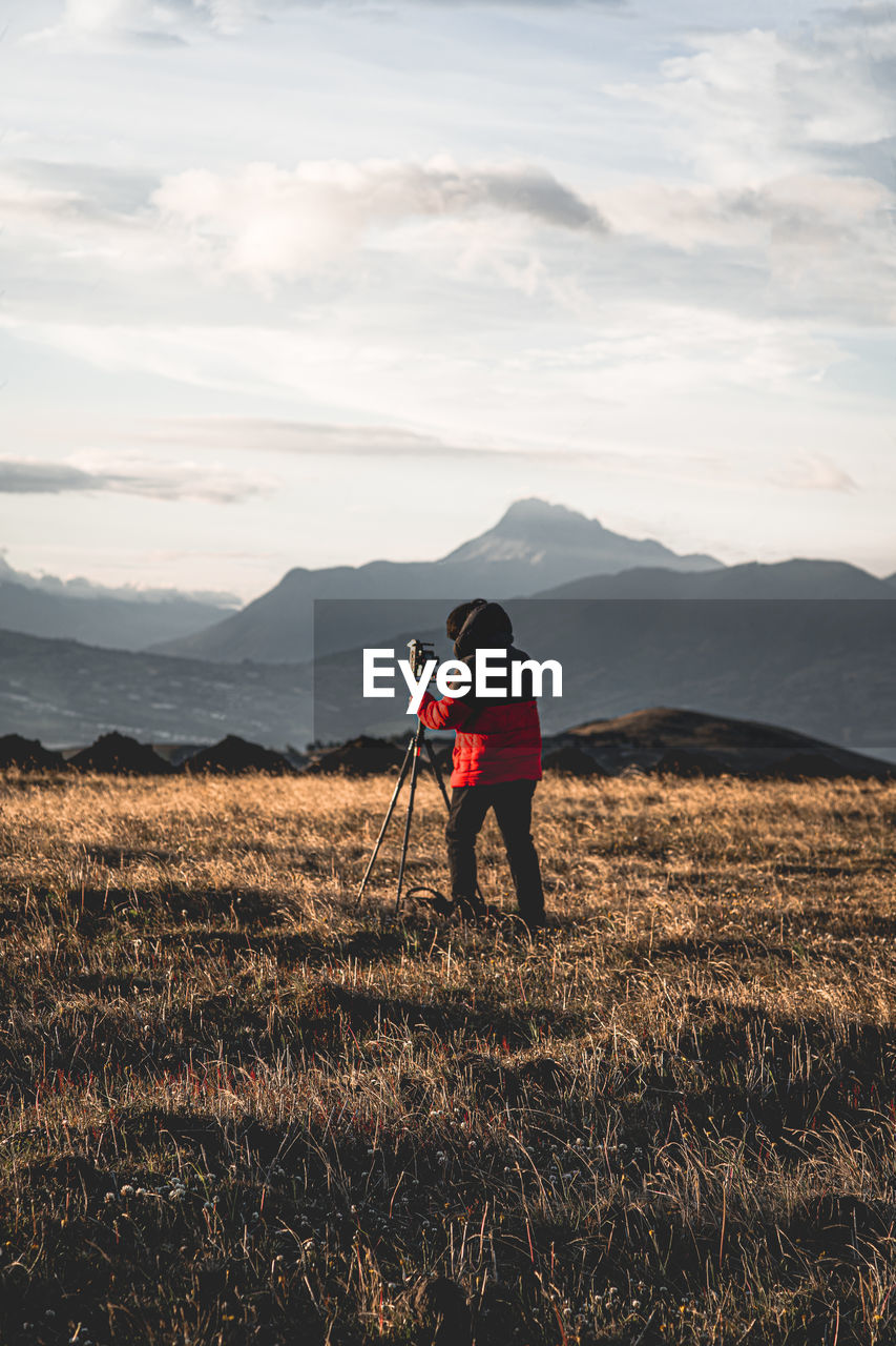 Full length of man photographing on field against sky