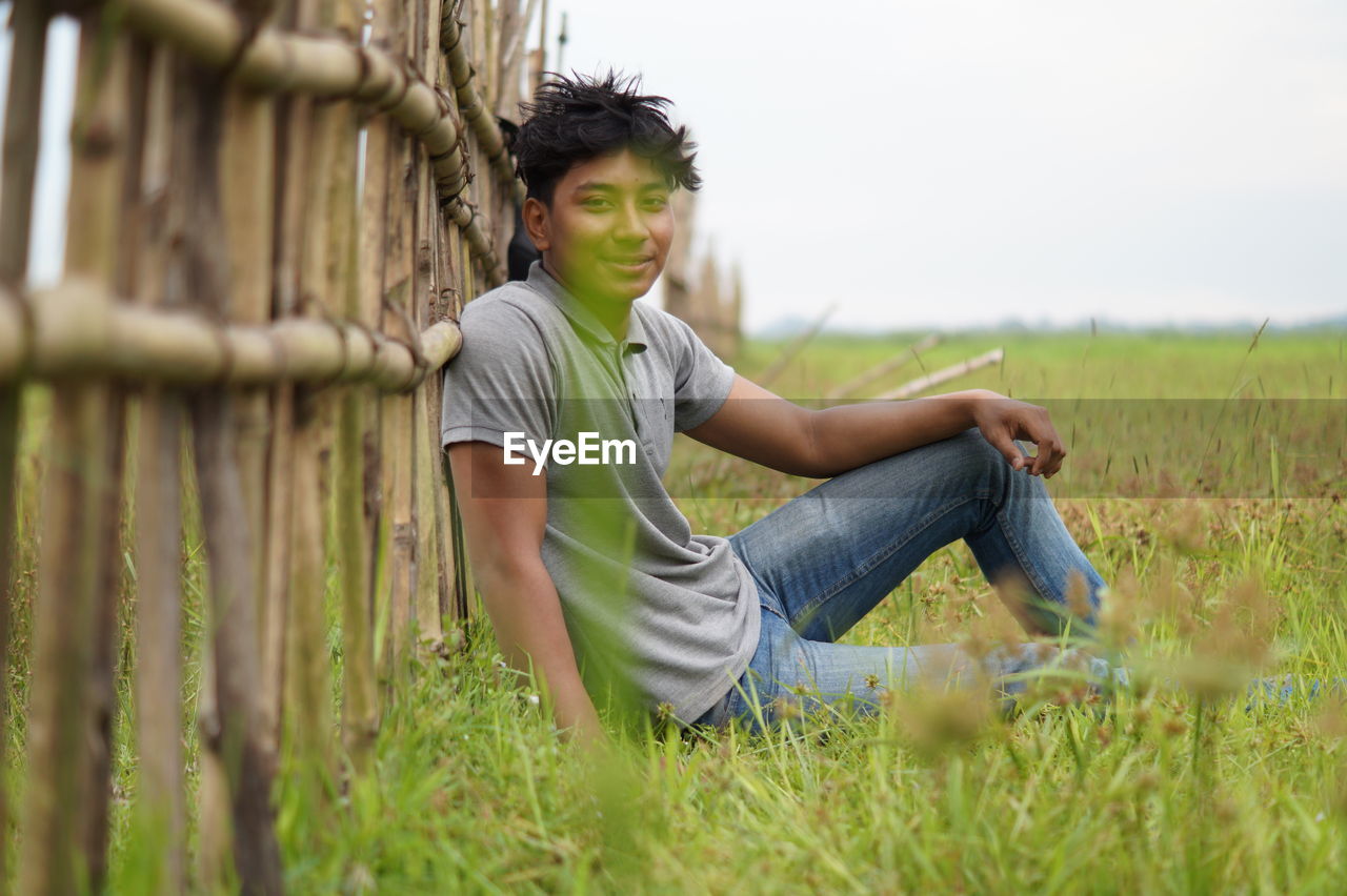 Portrait of smiling young man sitting on field