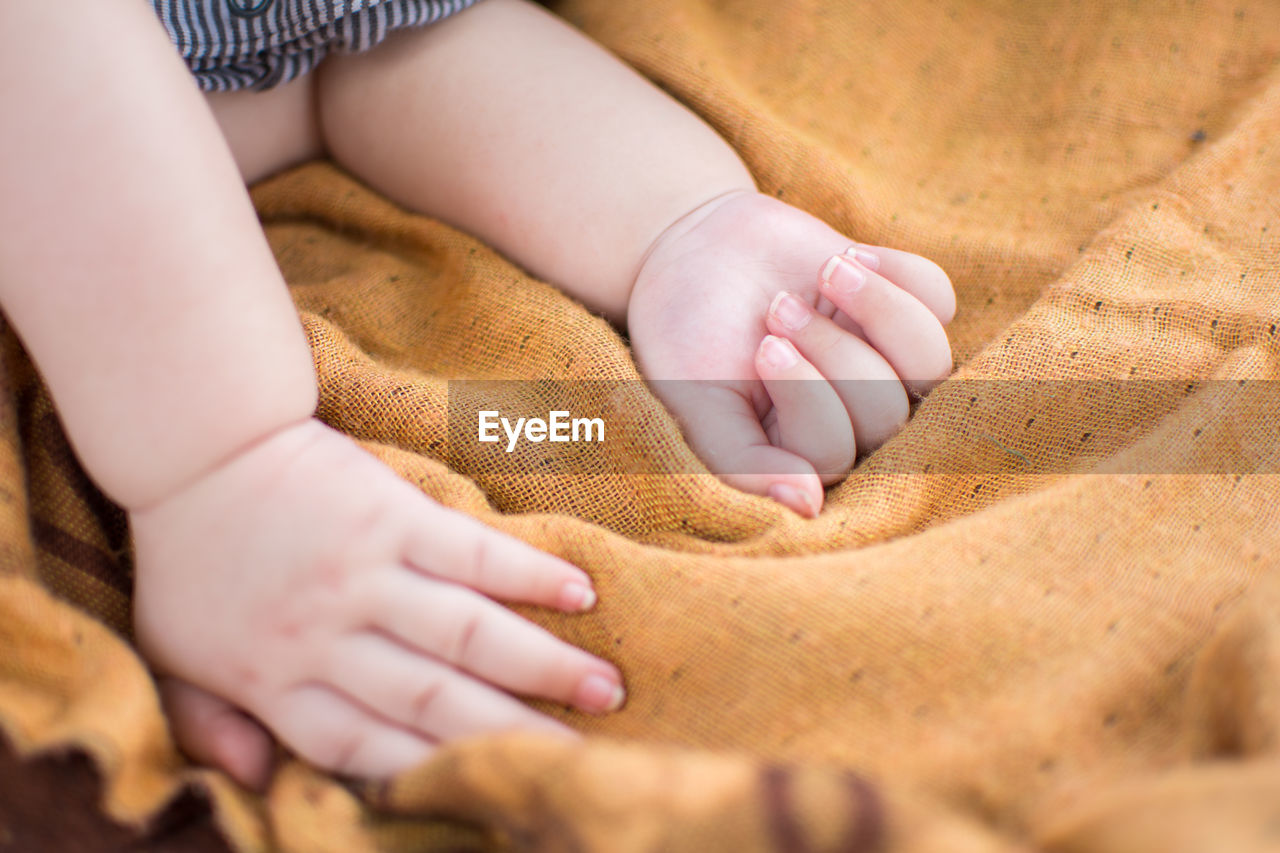 Cropped hand of baby on blanket