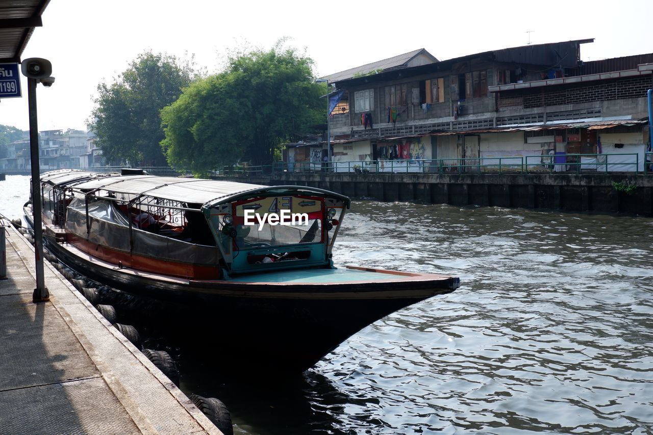 BOAT MOORED IN RIVER AGAINST SKY