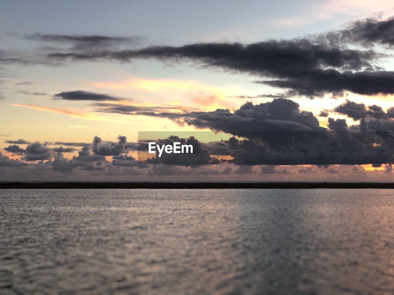 Scenic view of sea against dramatic sky during sunset