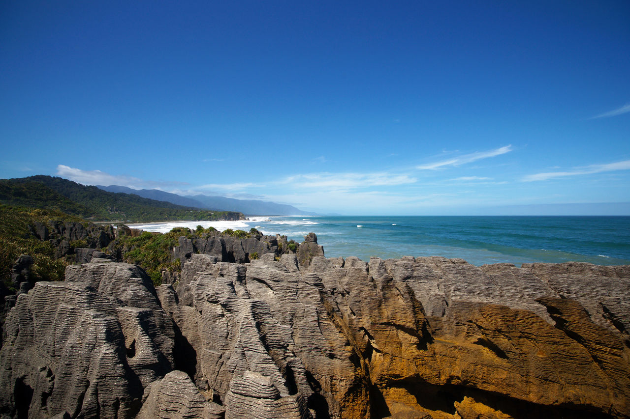 High angle view of pancake rocks by sea against blue sky