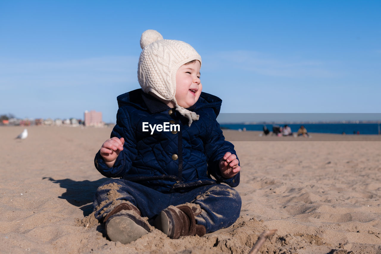 Extatic young boy is playing in the sand during in cold weather