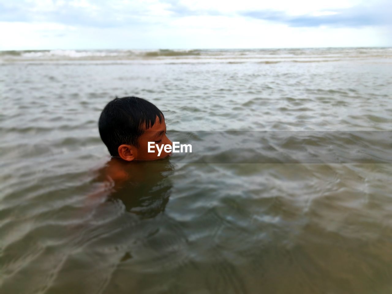 Boy swimming in sea against sky