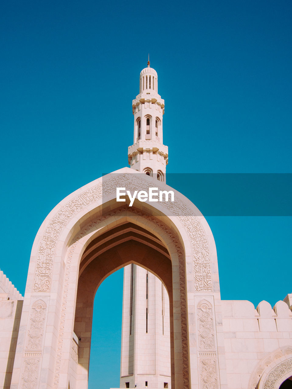 Low angle view of mosque entrance against clear blue sky