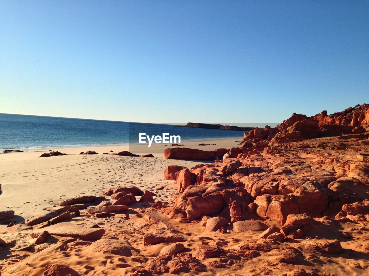 ROCKS ON BEACH AGAINST CLEAR BLUE SKY