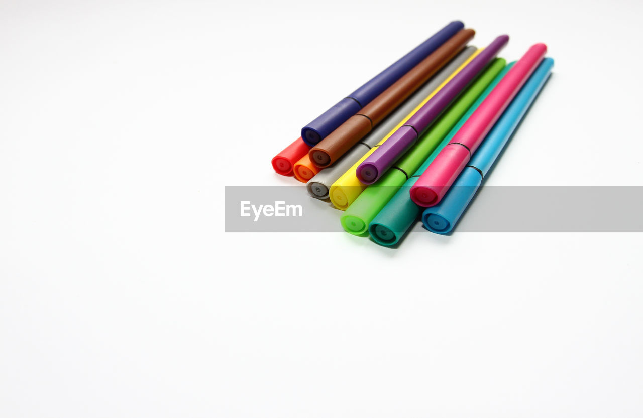 High angle view of multi colored felt tip pens against white background