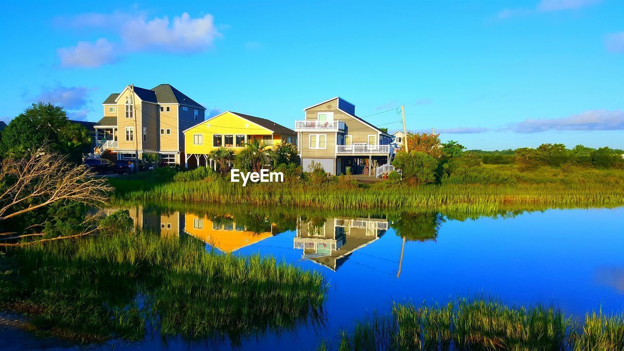 Houses by lake against blue sky