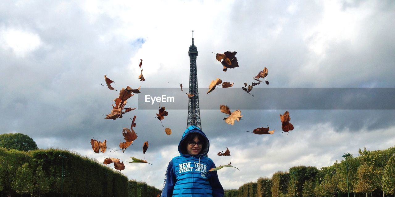 Low angle view of boy standing against eiffel tower