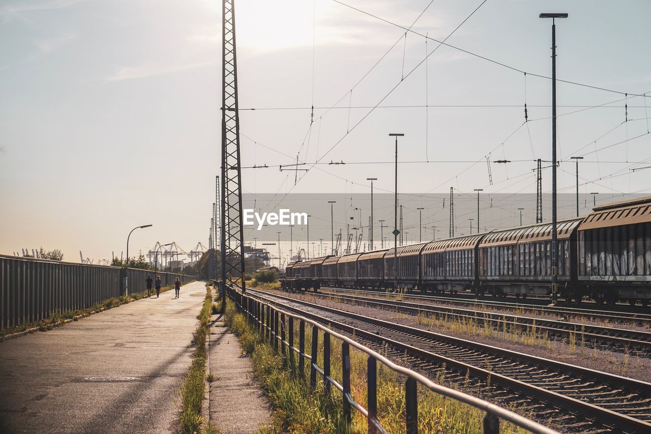 Train on railroad tracks against sky during sunny day