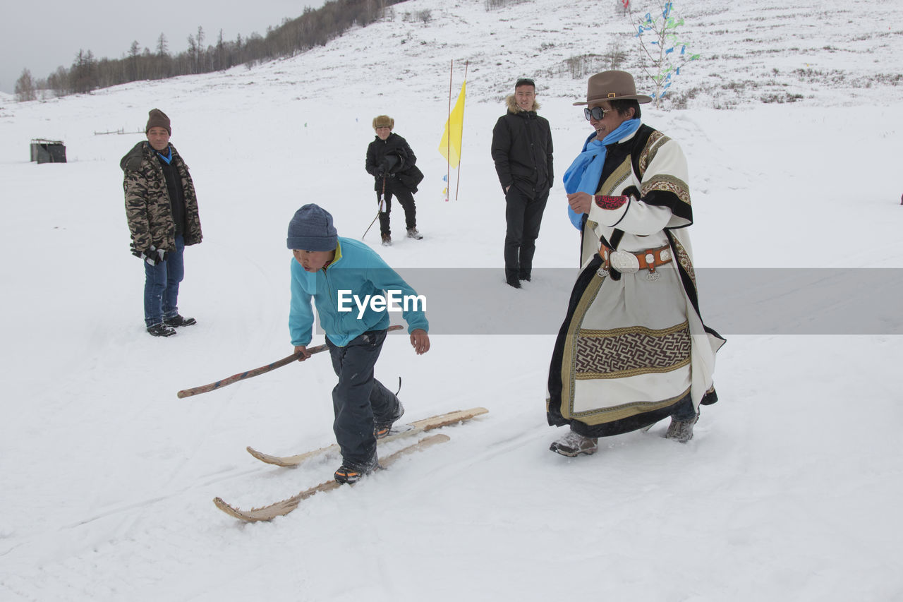 REAR VIEW OF PEOPLE STANDING ON SNOW