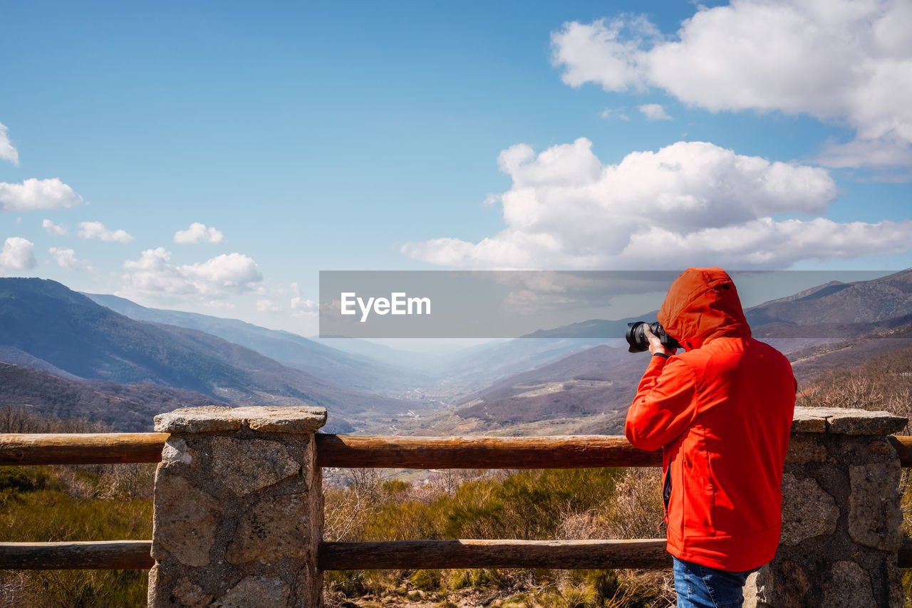 Unrecognizable photographer taking photos of the mountains with a blue sky with some clouds