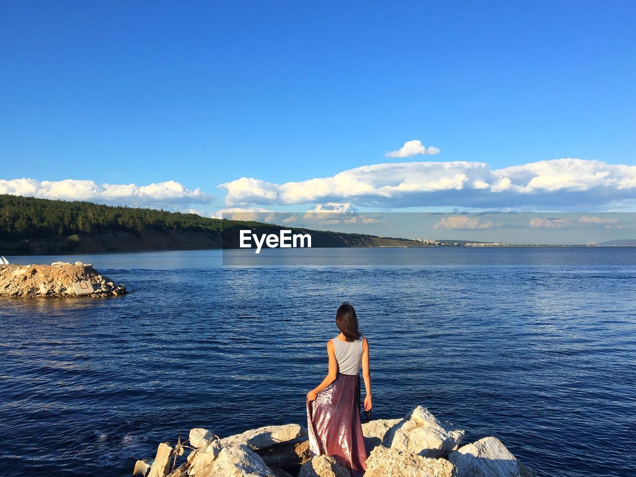 Rear view of woman looking at sea against blue sky