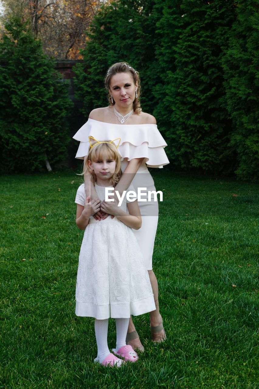 Portrait of mother and daughter in dress standing on field