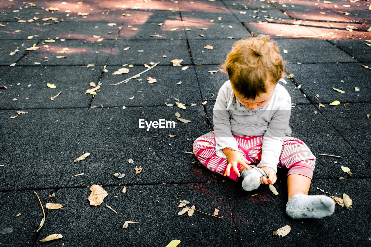 High angle view of girl playing with dry leaves