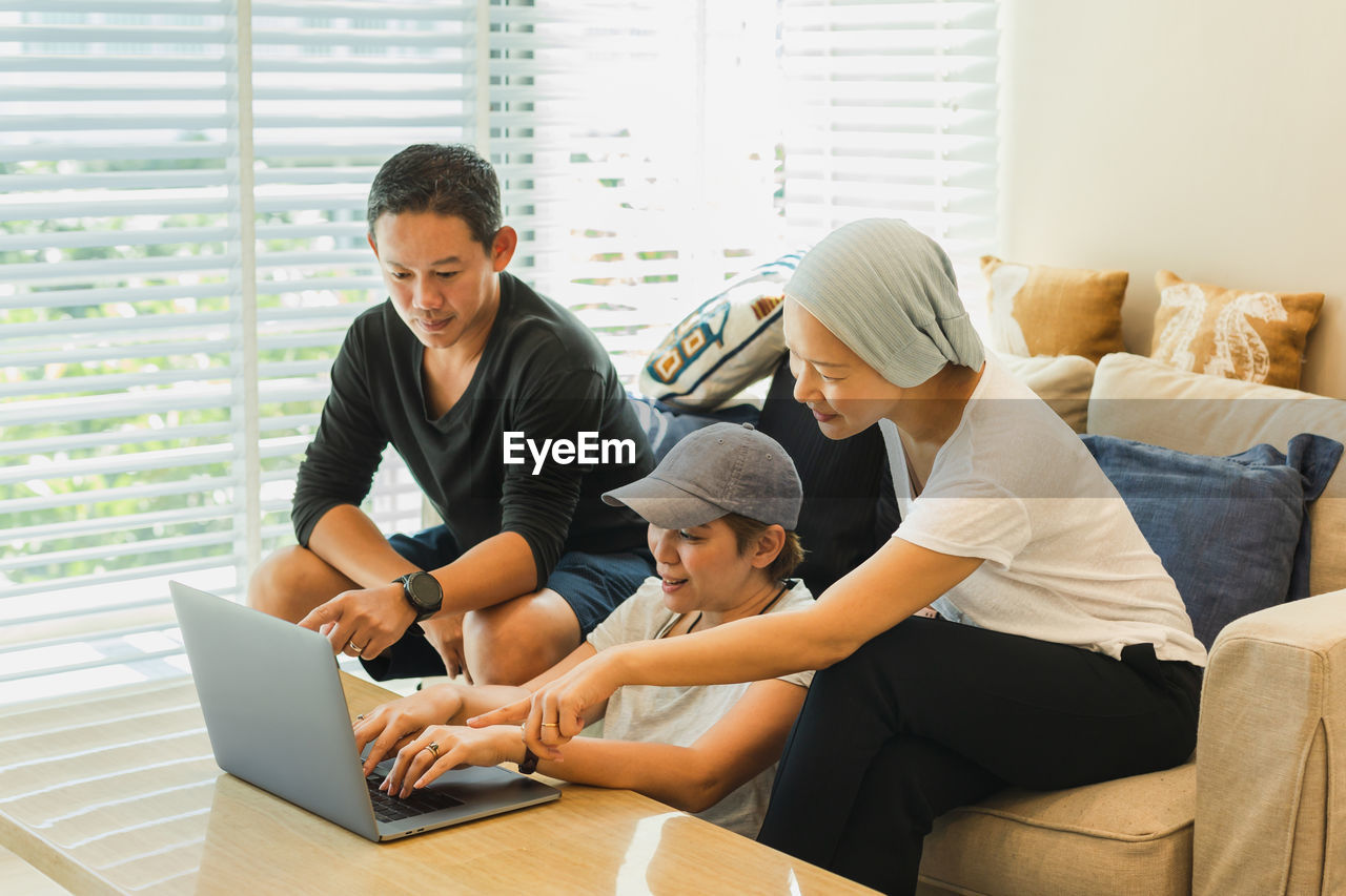 Three colleagues working on laptop at home.