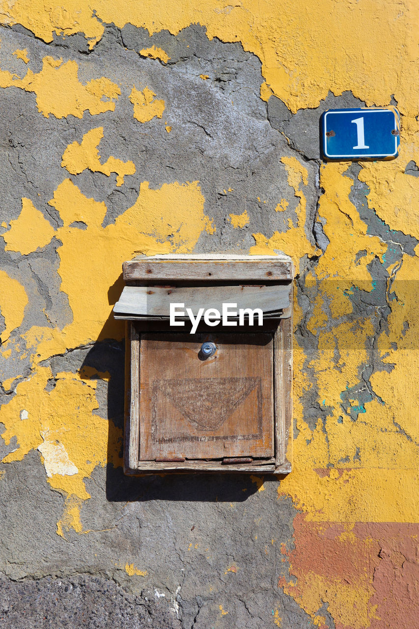 CLOSE-UP OF MAILBOX ON YELLOW WALL