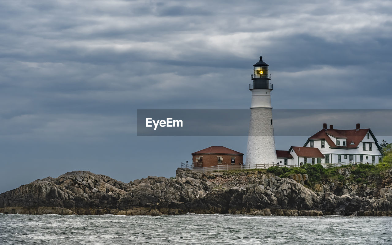 Lighthouse by sea against sky