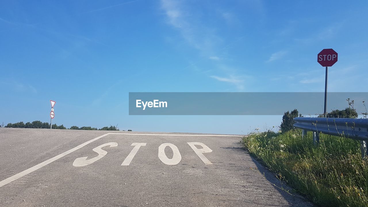 High angle view of stop text on road against blue sky