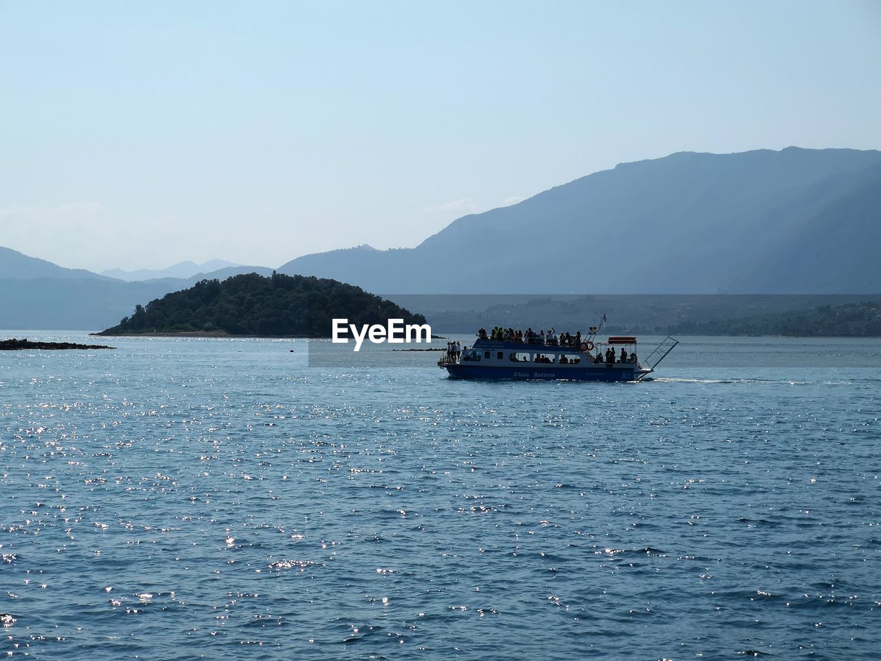 BOAT SAILING IN SEA AGAINST MOUNTAINS