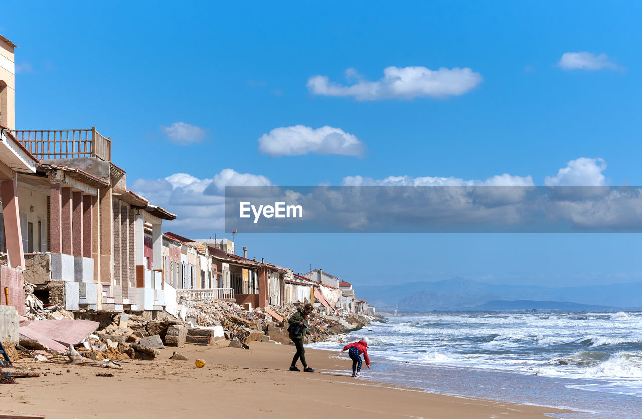 Father with child enjoying on shore at beach against sky at guardamar del segura