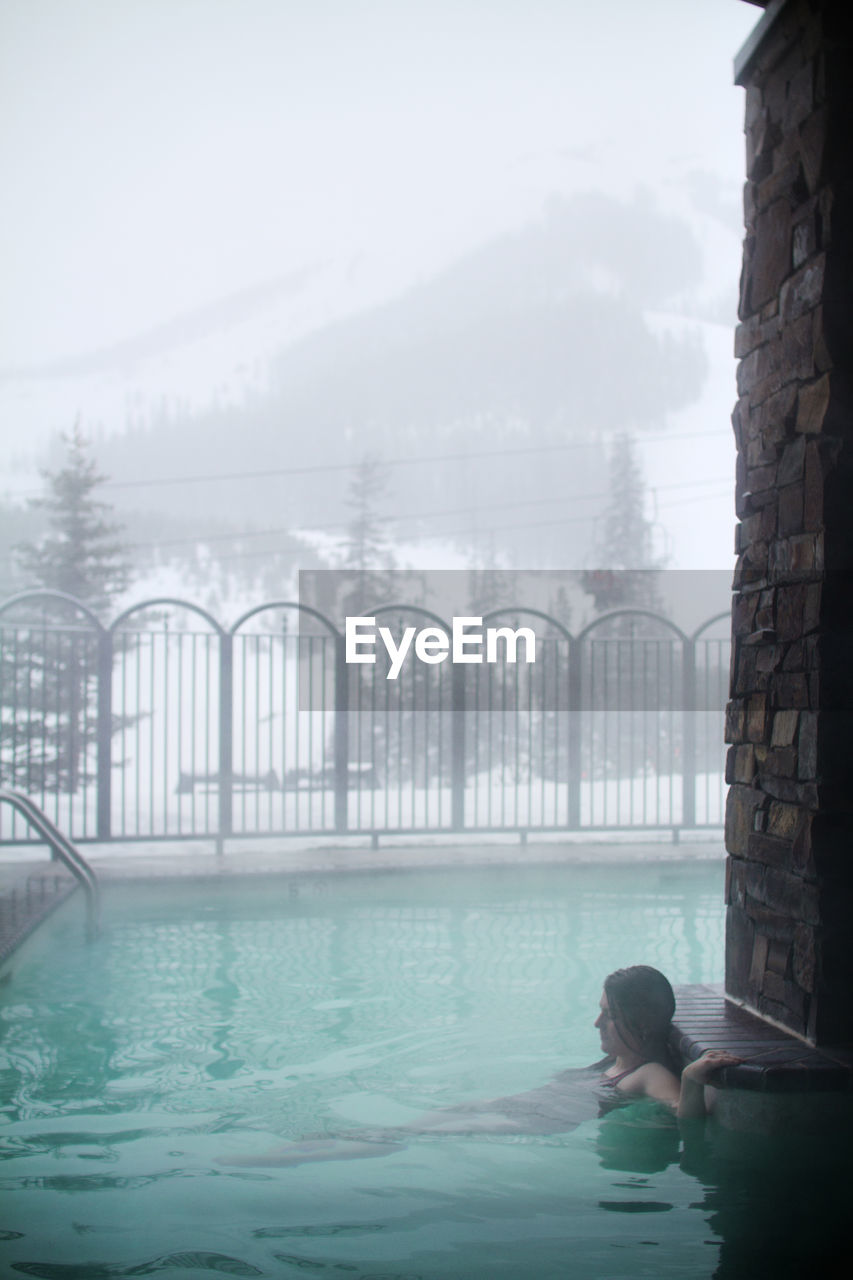 Woman relaxing in swimming pool at ski resort