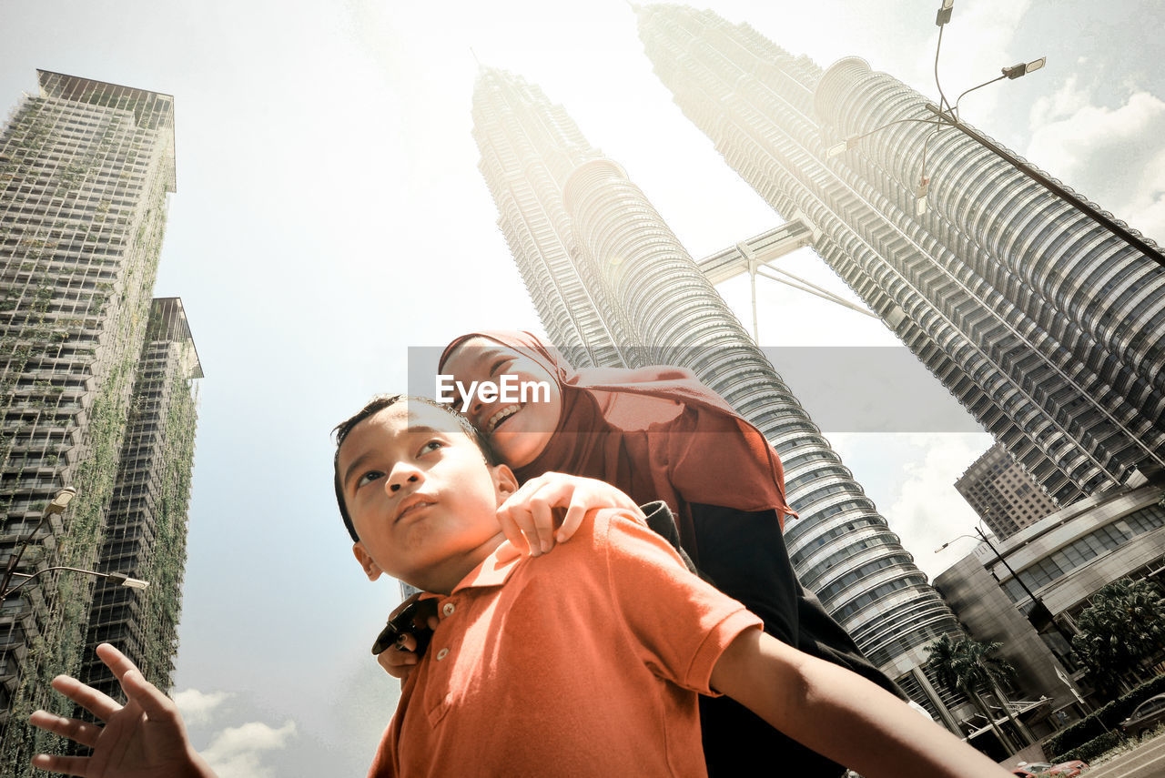 Low angle view of siblings against modern buildings